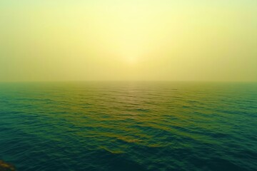 Obraz premium The ocean is calm and the sky is a beautiful shade of yellow