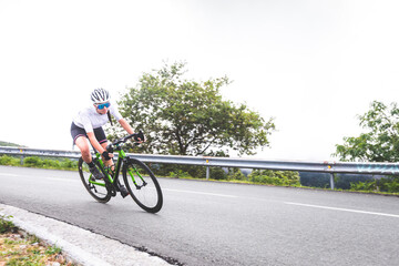 Young caucasian woman going downhill on a corner with a road bike on an asphalt road of a mountain.