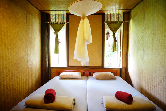 Interior of Asian wooden and bamboo bungalow bedroom with mosquito nets in Thailand