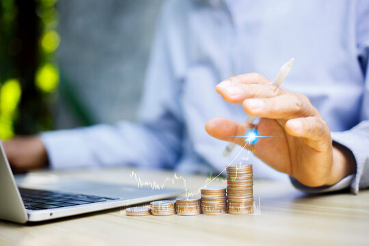 Compound interest and long-term investment concept. Business Hand touching glowing upward gold coins chart with bar graph and financial growth data on office background.
