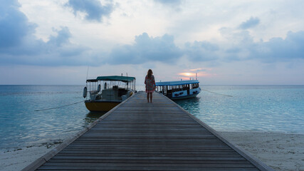 Woman standing in a pier in Maldives during sunset