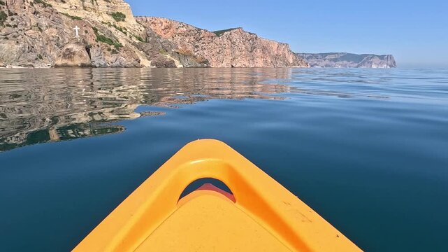 Kayak, Sea, Cliffs: serene view from a boat sailing towards rocky coastline on a clear day
