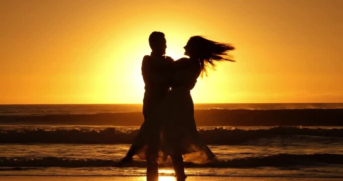 Happy couple dancing on beach at sunset
