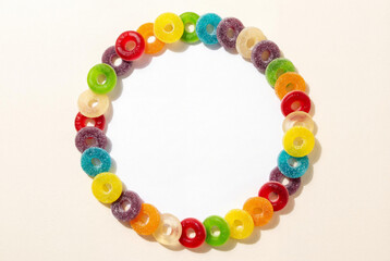 Top view of colorful fruit jelly candy ring frame with copy space in center on light background for birthday party celebration announcement