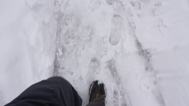 POV shot of a man walking through deep fresh snow in winter park, cinematic soft focus, 4K.
