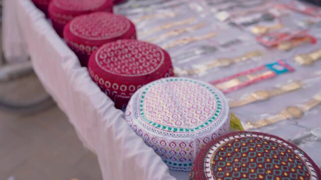 Close-up of colorful embroidered Sindhi topi caps and souvenir items on a street stall in Tharparkar, Sindh, Pakistan, highlighting local culture and crafts.