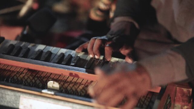 Close-up of hands playing a harmonium in Sindh, Pakistan, capturing traditional folk music performance with warm light and shallow depth of field.