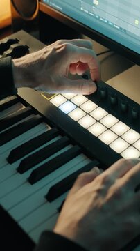 Music production. Man adjusting the knobs on a MIDI keyboard. Home studio