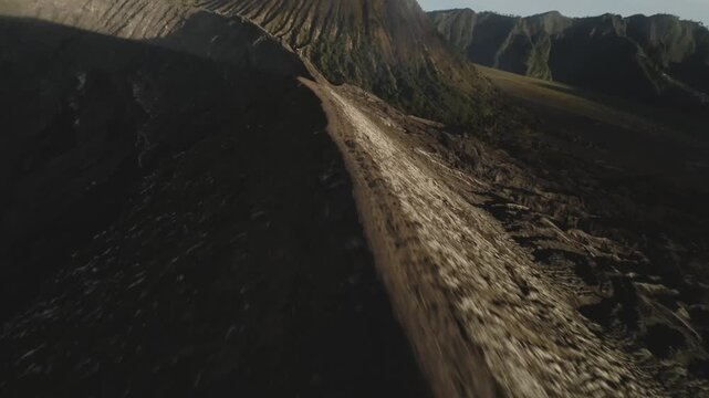 Epic FPV drone footage flying and diving around the Mount Bromo volcano crater at sunrise in East Java Indonesia showing volcanic landscape and morning light