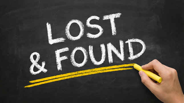 Hand writing Lost and Found on blackboard with yellow chalk
