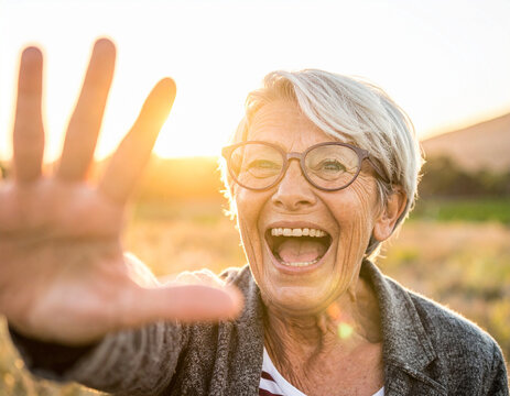 Lachende Seniorin hält die Hand zum high five hoch