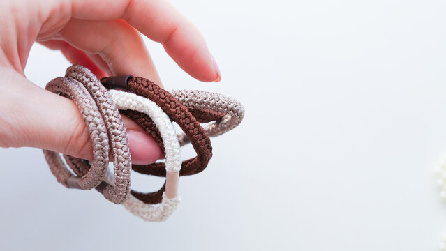 Hand holding multiple fabric hair ties in various colors and textures
