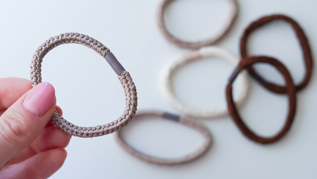 Hand holding fabric hair ties in various colors on a light background