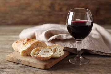 Sliced bread and red wine on rustic wooden table setting