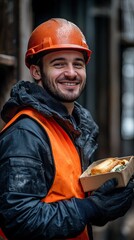Smiling worker, engineer in helmet, vest and work clothes, holding lunch, eating during break