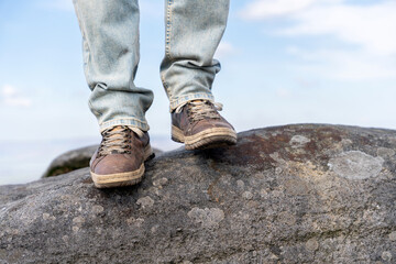 Standing on a rock near the sea during the day in a casual setting with blue sky and clouds