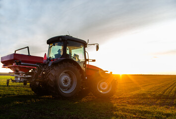 Tractor spreading artificial fertilizers in field