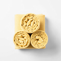 Detailed view of bright yellow rolled knit fabric stack on white background