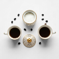 Elegant porcelain coffee cups with sugar bowl and roasted beans flat lay on white background