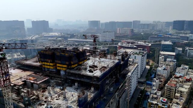 A drone view of a tower mid-build steel, Crane scaffolds, and safety nets wrap the structure as crews push vertical growth, reflecting rapid real-estate and commercial expansion.