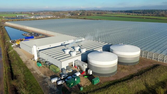 Aerial perspective of huge glass building for food crops powered by adjacent biogas renewable energy station in Bury St Edmunds United Kingdom