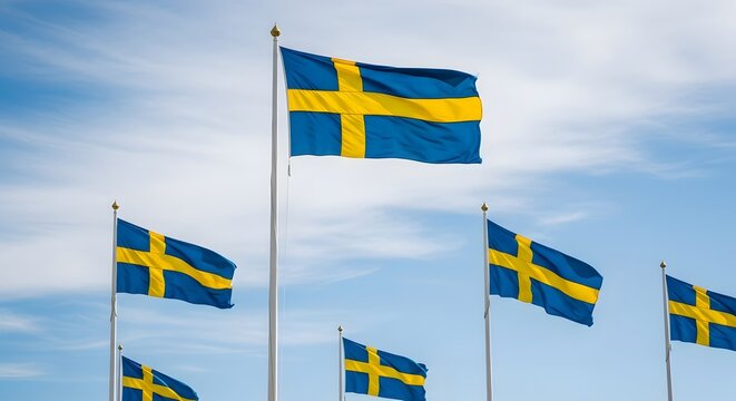 Multiple swedish flags waving in the wind against a cloudy sky