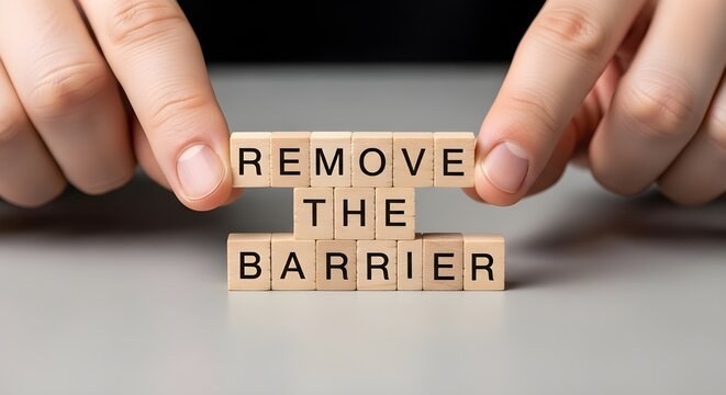 Hands placing wooden letter blocks spelling out the motivational phrase remove the barrier concept for success