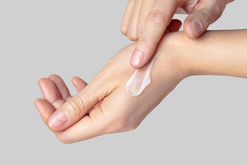 Fototapeta premium Close up photo woman hands with a white swatch sampled with a smear of cream. Self-care concept, skin care, hand care, facial care. Isolated gray background photo