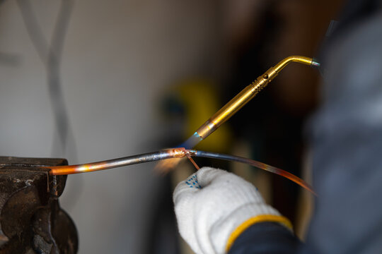 Close-up of a propane gas torch heating a copper pipe during a brazing or soldering process