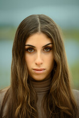 Naklejka premium Intense female portrait with a direct gaze and a blurred natural background