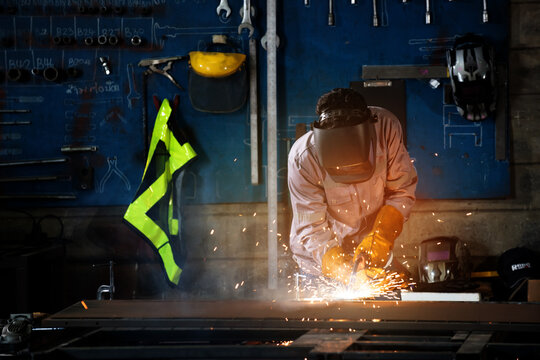 Welding welder spark workshop industrial factory technician metal safety helmet shape focused scene of hot work in dark metal shop, serving industrial plants as gloves and visor shield sparks