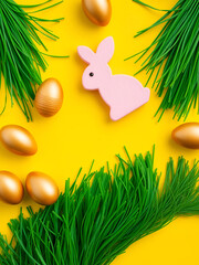 Creative Easter wave composition made from golden wooden eggs, pink marshmallow bunny and green grass on bright yellow background. Spring, easter concept. Flat lay, top view, copy space, square