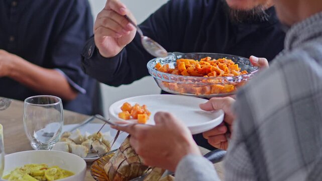 Close-up of man serving traditional Indonesian spicy fried potatoes during Eid al-Fitr family feast