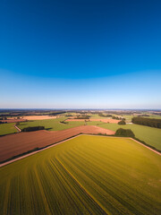 Aerial landscapes nature concept. A picturesque view of a vibrant green field under a clear blue sky.