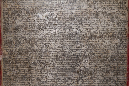 Close up of ancient pali scripture carved onto a marble slab.