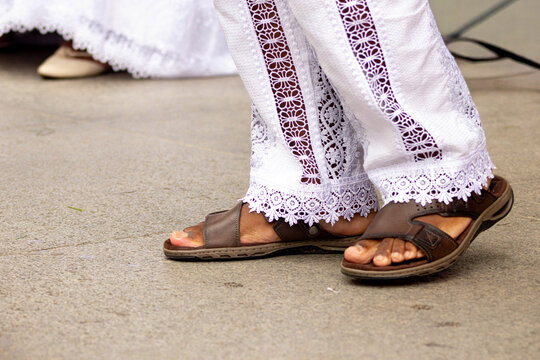 Cal&ccedil;a branca de renda e chinelo de couro. 
