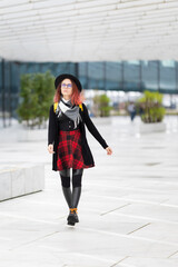Young woman with pink hair walking in urban plaza