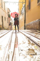 Fototapeta premium Stylish woman standing on tram tracks with umbrella