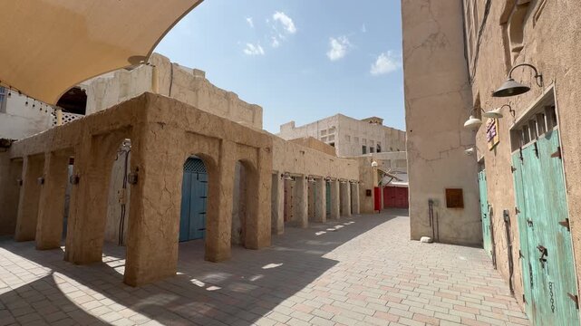Scenic views of Dubai's Al Seef heritage district featuring traditional Arabian architecture, wind towers, narrow alleyways, and waterfront scenery along the creek during a sunny day.

