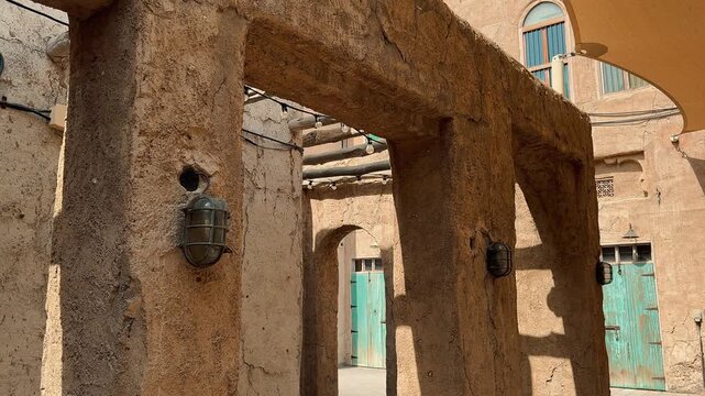 Scenic views of Dubai's Al Seef heritage district featuring traditional Arabian architecture, wind towers, narrow alleyways, and waterfront scenery along the creek during a sunny day.

