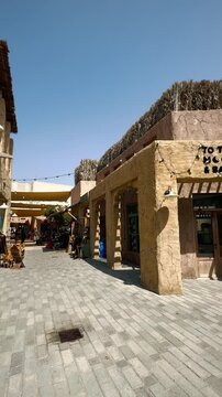 Scenic views of Dubai's Al Seef heritage district featuring traditional Arabian architecture, wind towers, narrow alleyways, and waterfront scenery along the creek during a sunny day.

