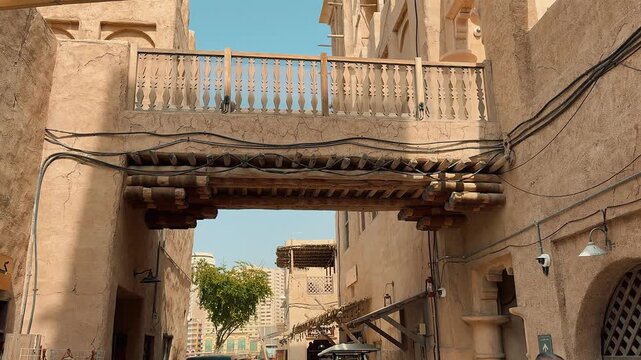 Scenic views of Dubai's Al Seef heritage district featuring traditional Arabian architecture, wind towers, narrow alleyways, and waterfront scenery along the creek during a sunny day.

