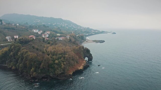 Aerial view of Delikli Tas natural rock arch in Giresun, Turkey. Scenic Black Sea coastline with sea caves and foggy mountain landscape.