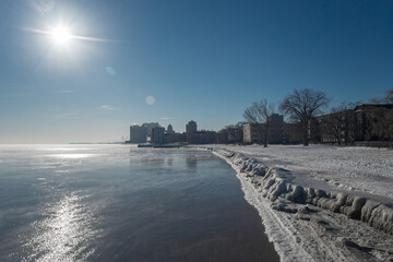A bright sun shines over a frozen lakefront