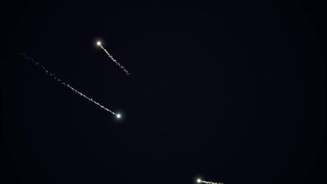 Luminous streaks of light illuminate the dark night sky, leaving glowing trails