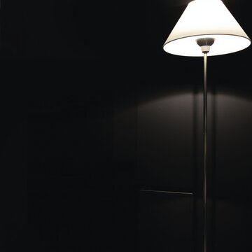 A modern bulb glows within a dark room, casting warm illumination from a sleek lamp mounted on the wall to complement the interior design and home decor