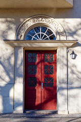 Old wooden door with window above it featuring decorative elements in the historic district of Rixdorf in Berlin.