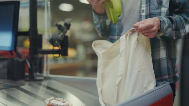 Person carefully loads produce into reusable bag, Casual shopper arranges bananas inside ecofriendly cotton tote