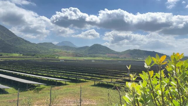 Long rows of solar panels stretch across a rural field, forming a modern energy landscape against rolling hills and open sky. Green technology.