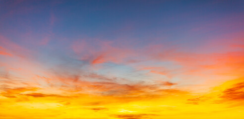 Fototapeta premium Vibrant sunset sky with dramatic orange and purple clouds,A breathtaking sunset sky featuring a beautiful gradient of deep purple, fiery orange, and golden yellow. The wispy cirrus clouds 